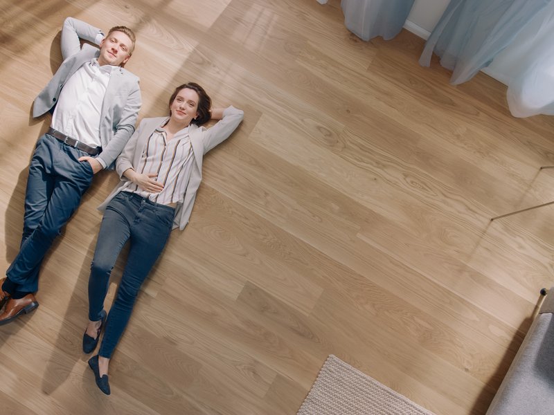 young couple laying on empty floor